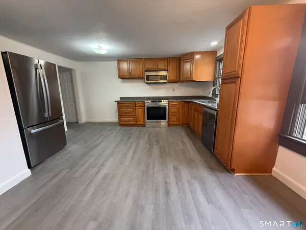 an empty room with wooden floor cabinet and windows