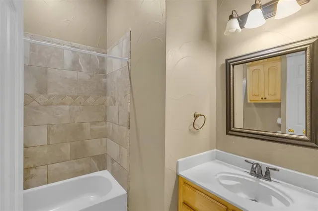 a bathroom with a granite countertop sink a mirror and a bathtub