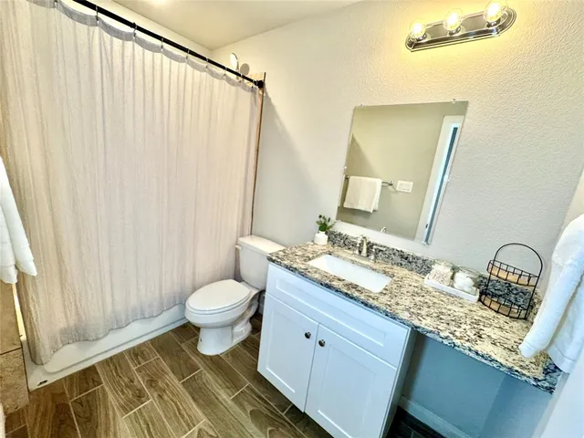 a bathroom with a granite countertop sink toilet and mirror