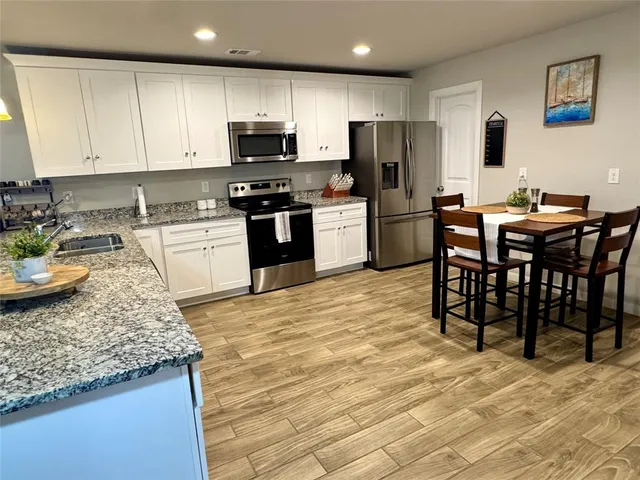 a kitchen with kitchen island granite countertop a sink appliances and cabinets