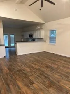 a view of kitchen and empty room with wooden floor