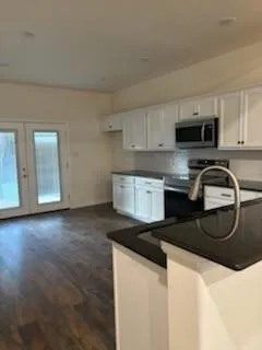 a kitchen with granite countertop a stove a sink and a microwave