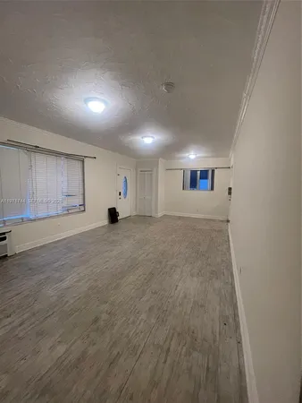 an empty room with a rug and a window