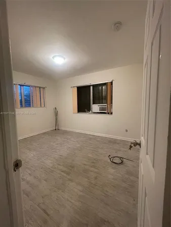 a view of an empty room with wooden floor and closet