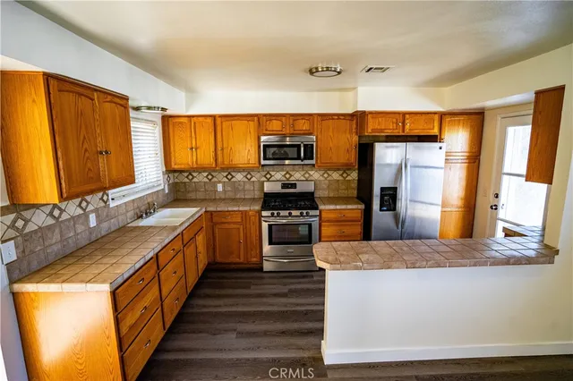 a large kitchen with stainless steel appliances granite countertop a stove a sink and a refrigerator