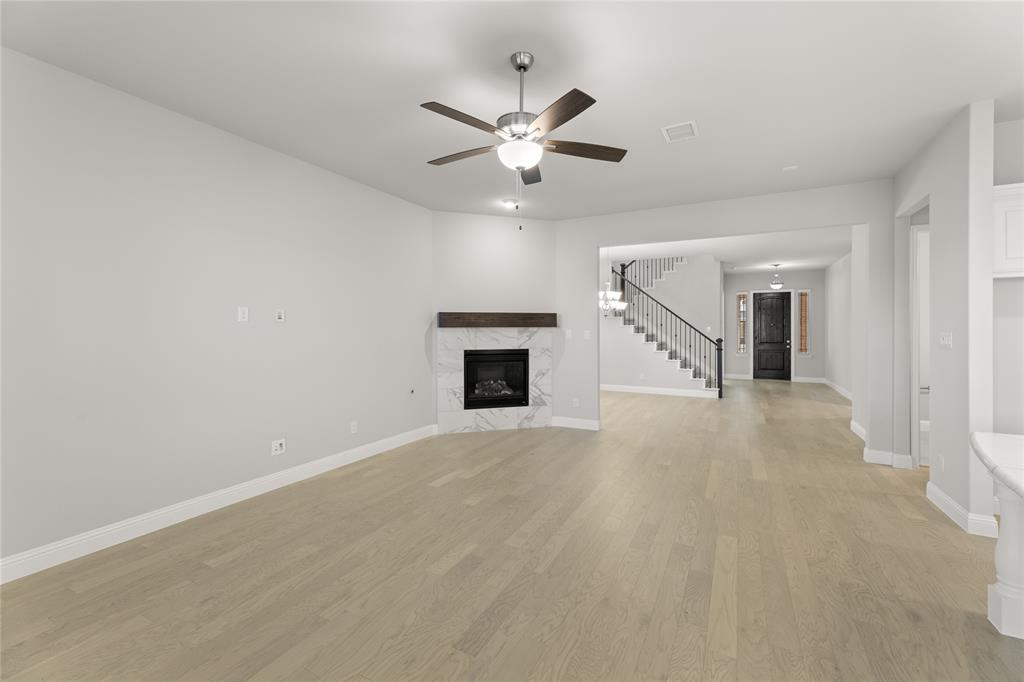 3539 Helios Lane Corinth, TX 76208 - Photo 13 of 33 en empty room with a ceiling fan and a fireplace