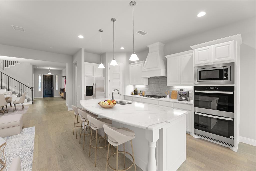 3539 Helios Lane Corinth, TX 76208 - Photo 2 of 33 a kitchen with a stove a microwave and a view of living room