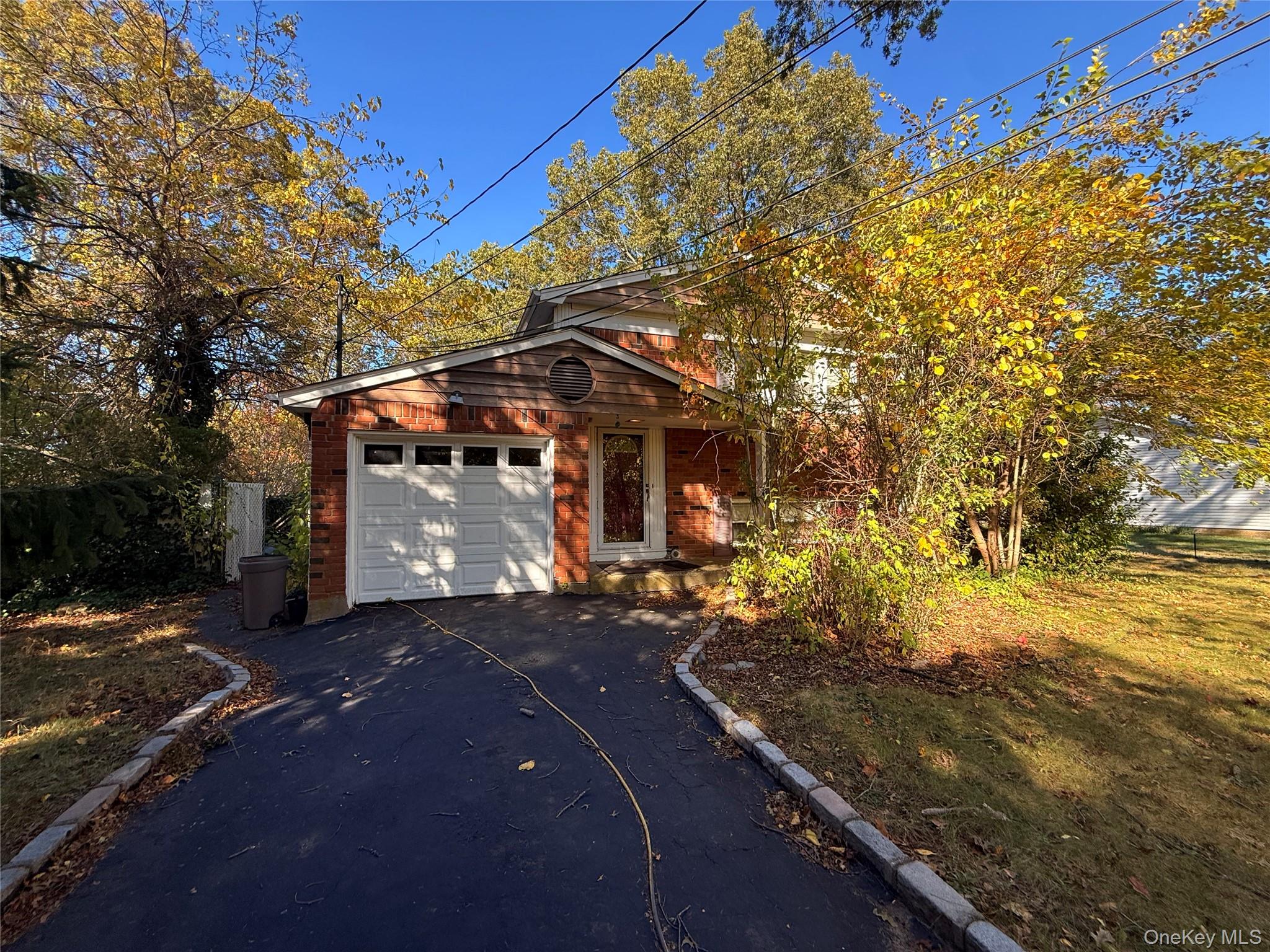 View of front of home with asphalt driveway, an attached garage, and brick siding