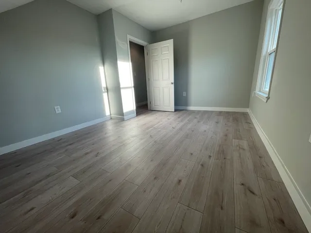 a view of an empty room with wooden floor and windows