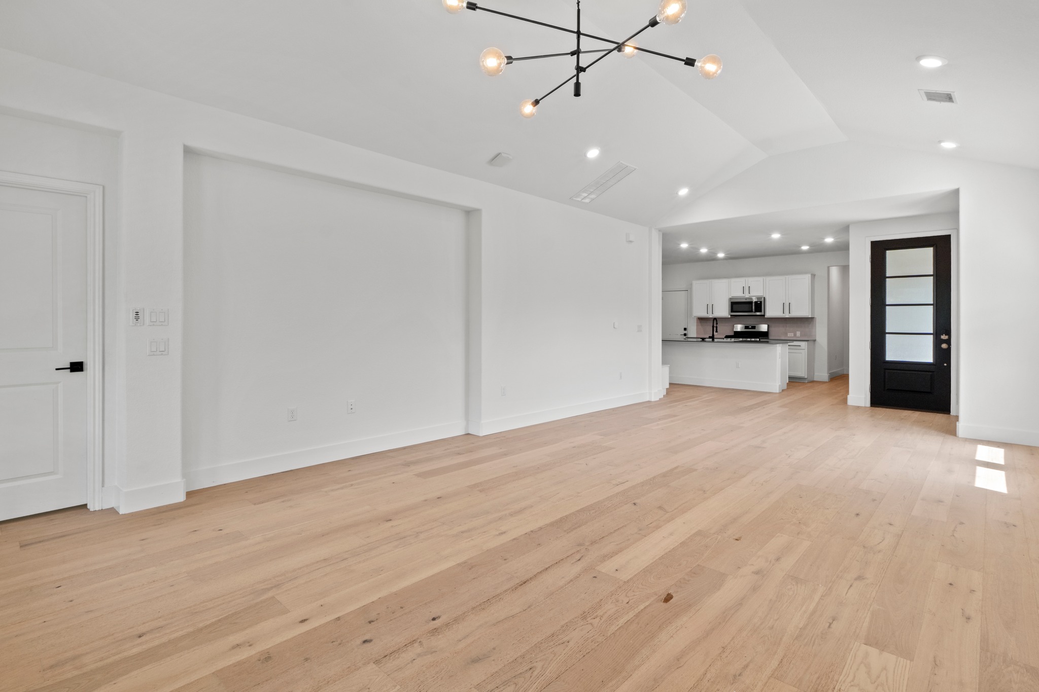 1101 Skeeter Cove Austin, TX 78748 - Photo 6 of 31 Blonde hardwood floors complement crisp white walls and modern overhead lighting.