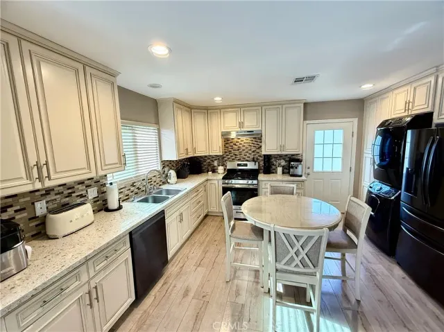 a kitchen with sink a refrigerator and chairs
