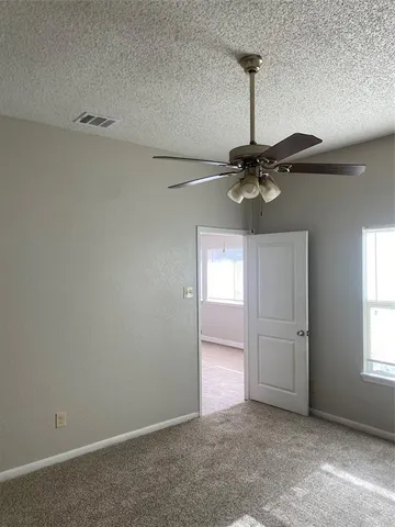 an empty room with windows and fan