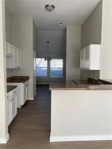 a kitchen with stainless steel appliances a large counter top a stove a sink a refrigerator white cabinets and wooden floor