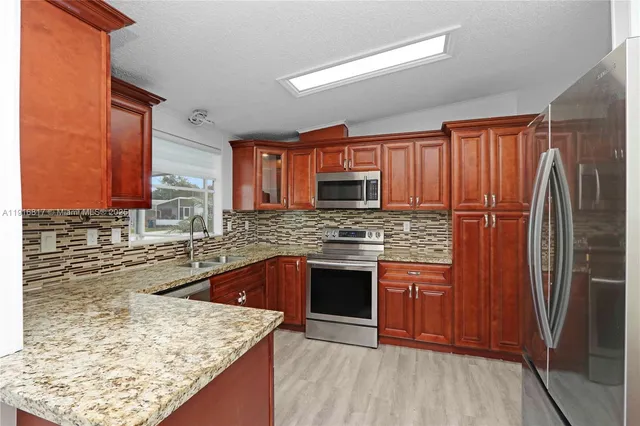 a kitchen with stainless steel appliances granite countertop wooden cabinets and a refrigerator
