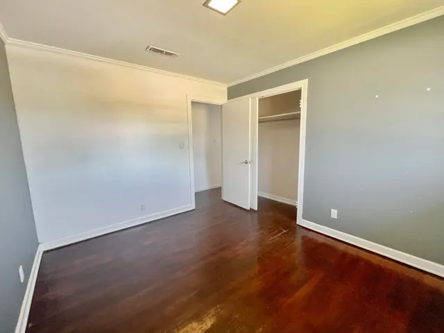 a view of an empty room with wooden floor and closet