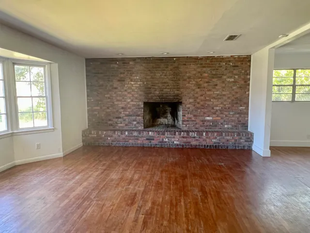 a view of empty room with wooden floor and fireplace
