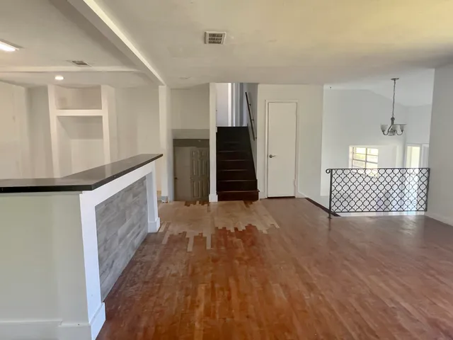 a view of an empty room with wooden floor and staircase