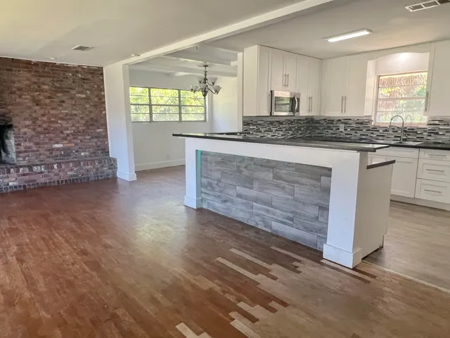 a kitchen with granite countertop a stove a sink and white cabinets with wooden floor