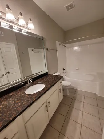 a bathroom with a granite countertop sink a toilet and a mirror