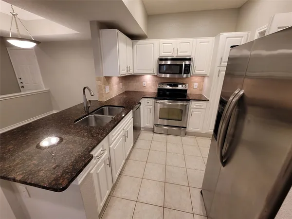 a kitchen with stainless steel appliances granite countertop a sink refrigerator and microwave