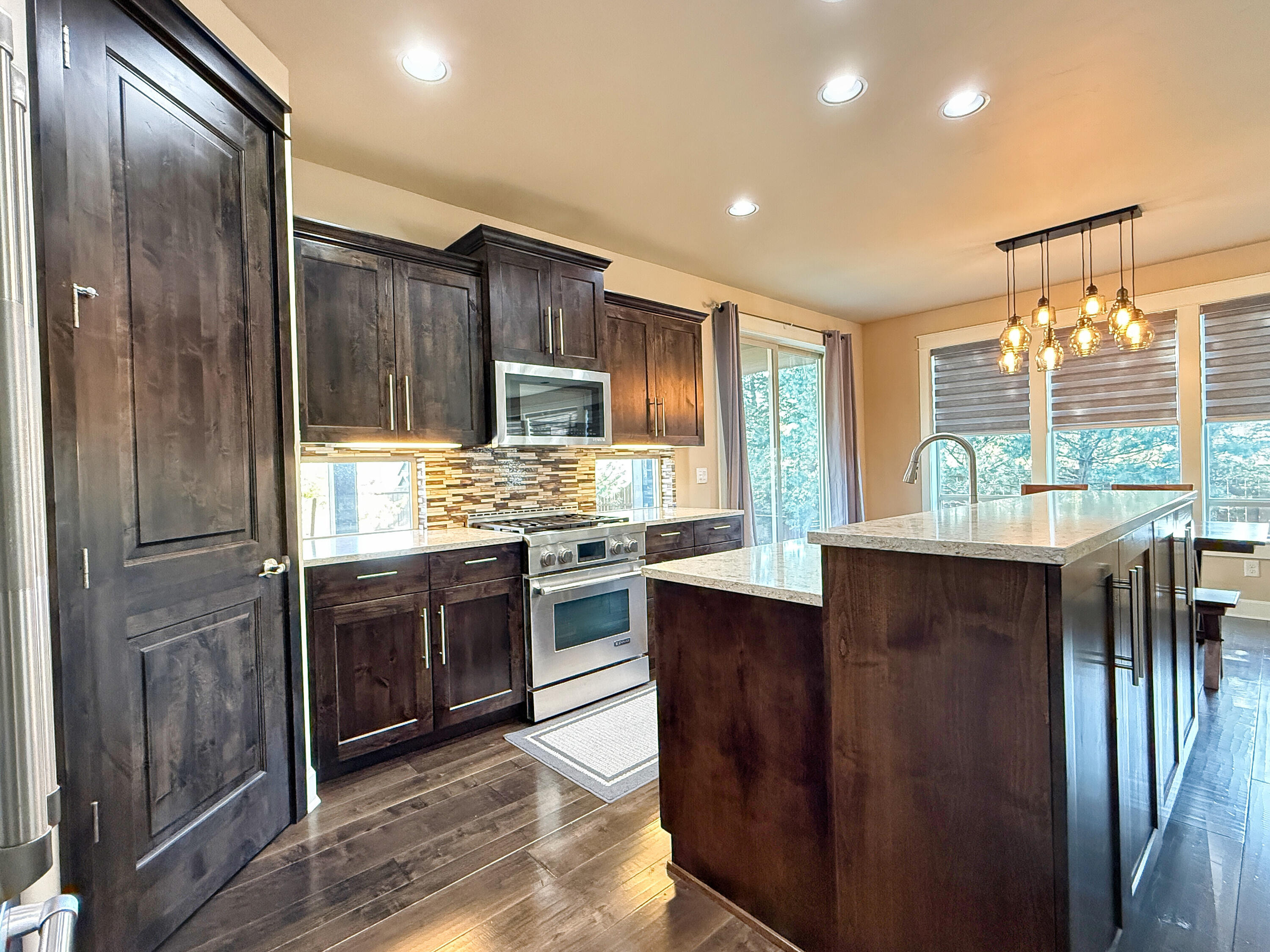 61072 Manhae Loop Bend, OR 97702 - Photo 4 of 63 a kitchen with stainless steel appliances granite countertop a refrigerator a sink dishwasher a stove and a dining table with wooden floor