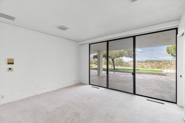 a view of a house with a large window and a yard with plants and large tree