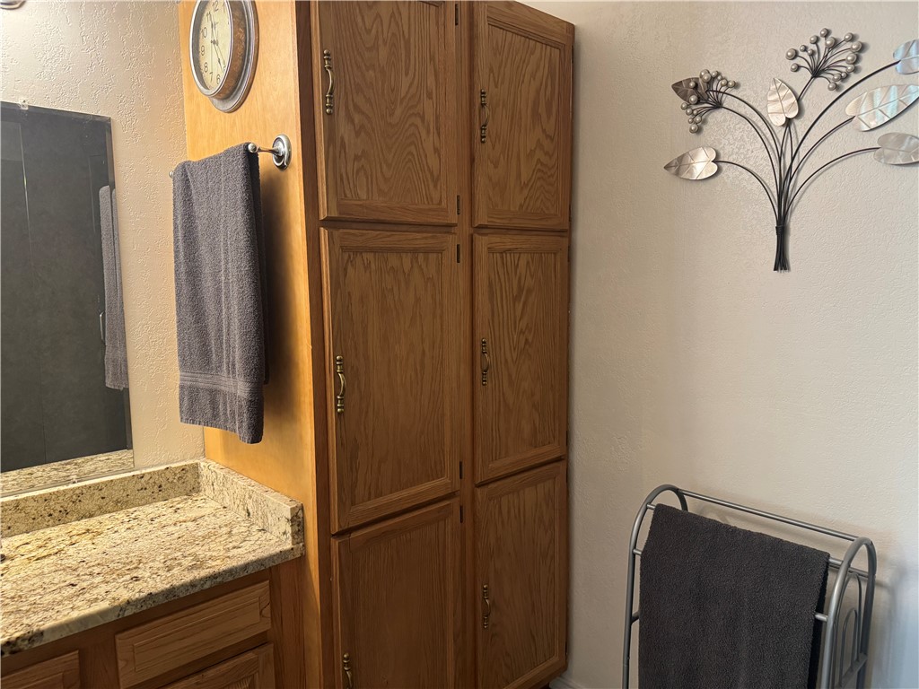 95 Deer Run Road Delaware, AR 72835 - Photo 34 of 40 Bathroom featuring a wood-finish storage cabinet with brass-tone hardware, a vanity with a light-toned stone countertop, and a wall-mounted mirror