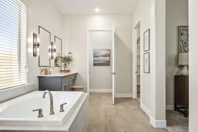 a bathroom with a tub a sink and a large mirror