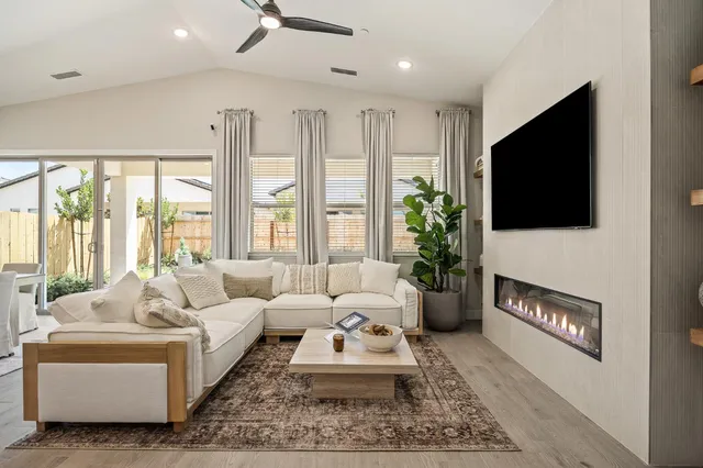 a living room with furniture a flat screen tv and a floor to ceiling window