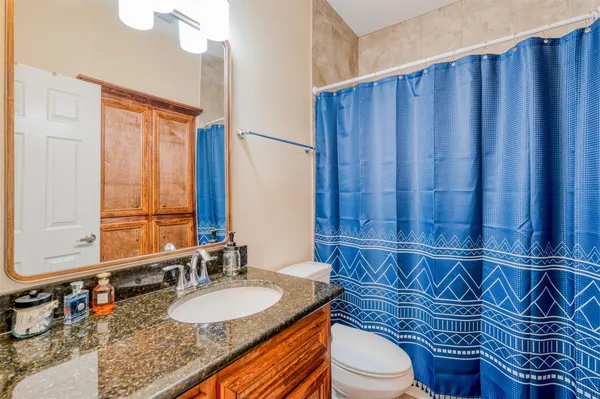 a bathroom with a granite countertop toilet sink and mirror