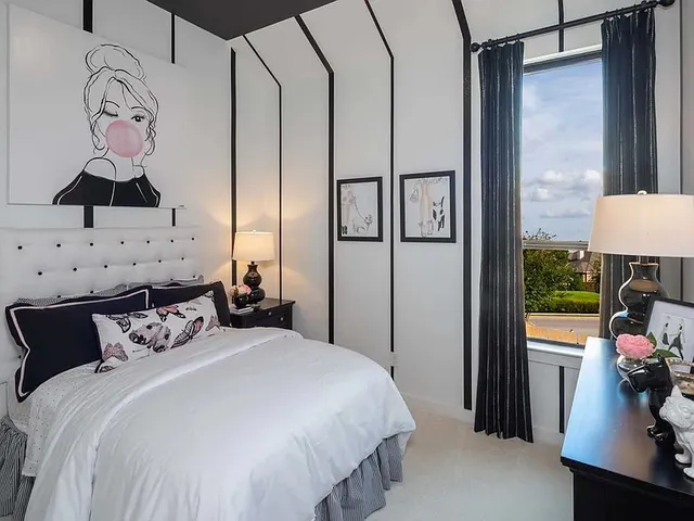 a bedroom with a bed and a lamp on table with wooden floor