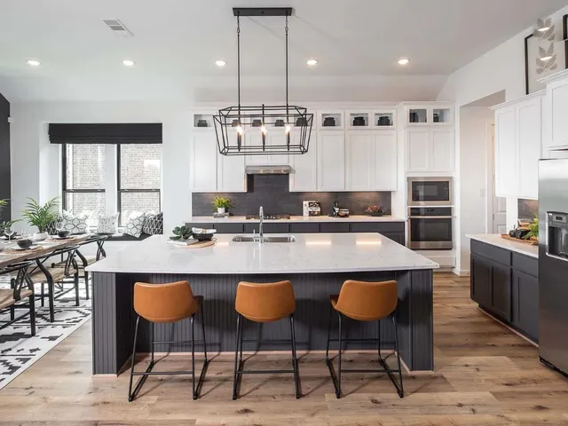 a kitchen with kitchen island granite countertop a stove a sink a refrigerator and chairs