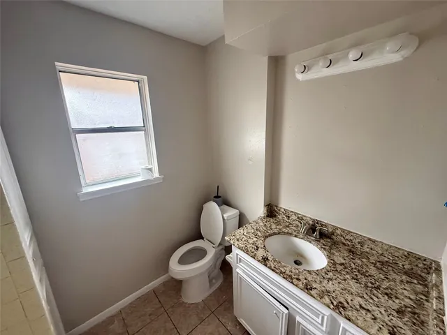 a bathroom with a granite countertop sink and a toilet