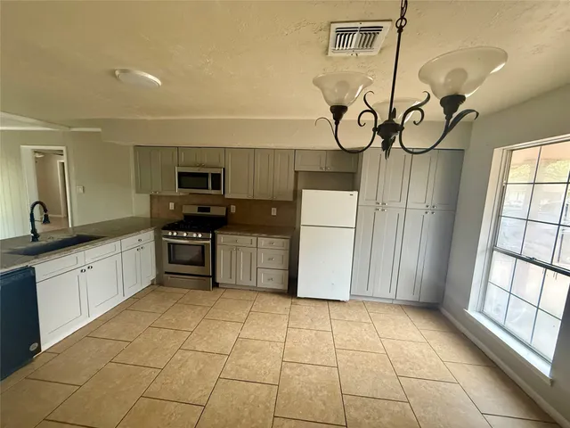 a kitchen with stainless steel appliances granite countertop a stove a sink a granite counter top and a refrigerator