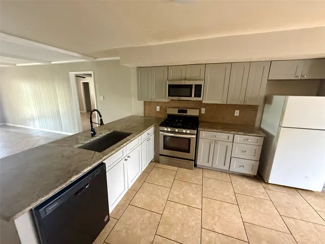 a large kitchen with a stove a sink dishwasher and a refrigerator