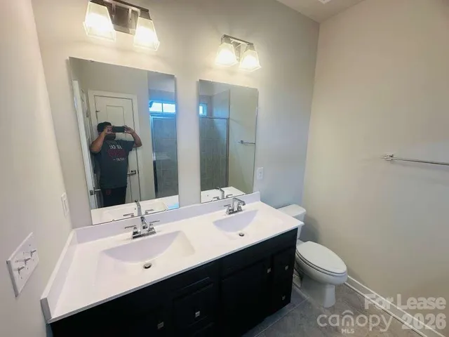 a bathroom with a double vanity sink toilet and mirror