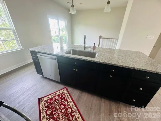a kitchen with granite countertop a sink and a wooden floor