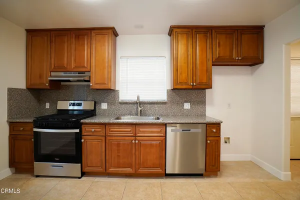 a kitchen with stainless steel appliances granite countertop wooden cabinets a stove a sink and dishwasher