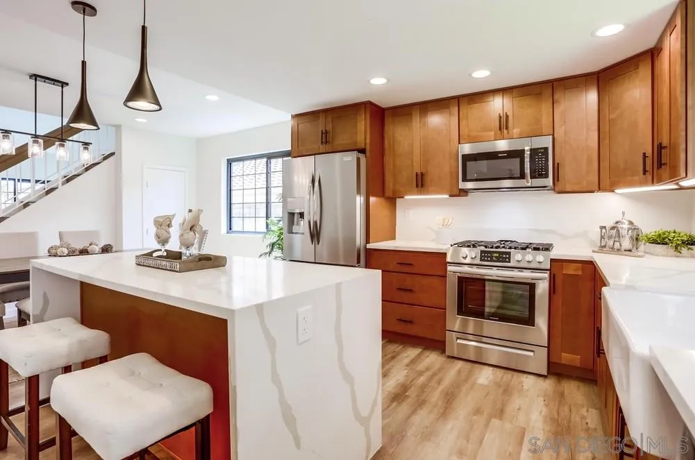 916 Alyssum Road Carlsbad, CA 92011 - Photo 16 of 42 a kitchen with stainless steel appliances a stove a sink a refrigerator white cabinets and wooden floor