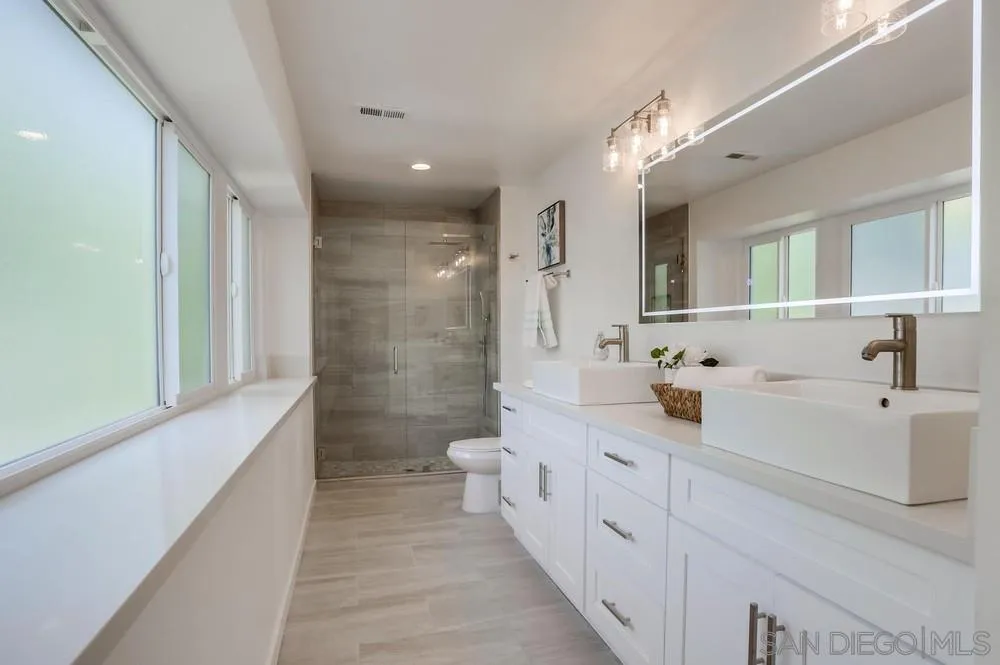 916 Alyssum Road Carlsbad, CA 92011 - Photo 26 of 42 a spacious bathroom with double vanity a mirror and a shower