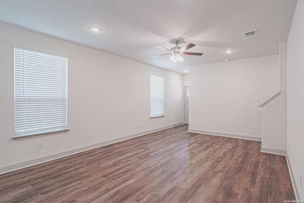 an empty room with wooden floor chandelier and windows