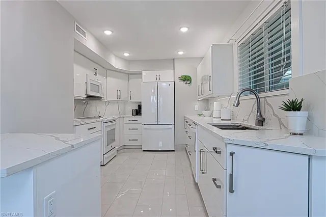 a kitchen with white cabinets and white appliances