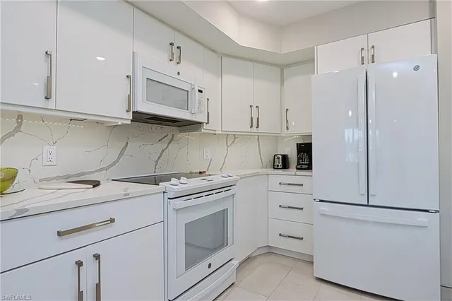 a kitchen with white cabinets and white appliances