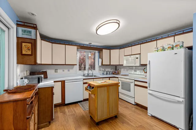 a kitchen with a refrigerator a white cabinets and wooden floor