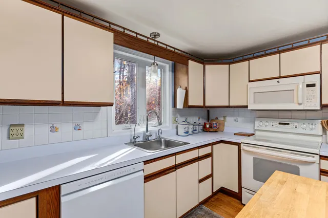 a kitchen with stainless steel appliances white cabinets a sink and a window