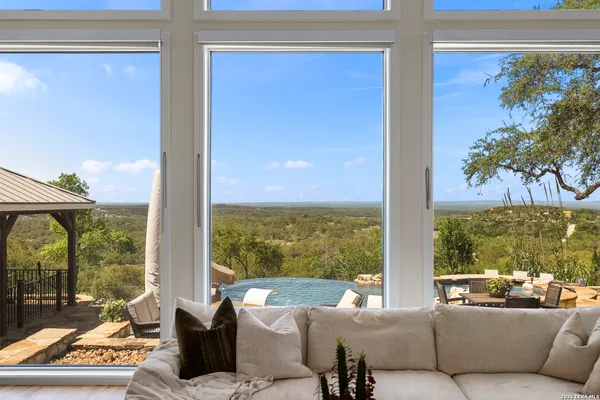 a living room with patio furniture and floor to ceiling windows