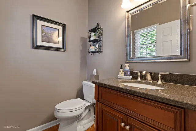 a bathroom with a granite countertop toilet sink and mirror