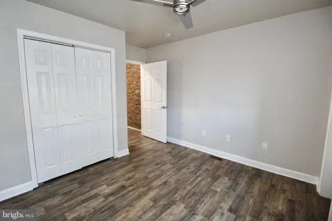 a view of an empty room with closet and wooden floor