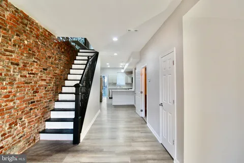 a view of a hallway with wooden floor and stairs