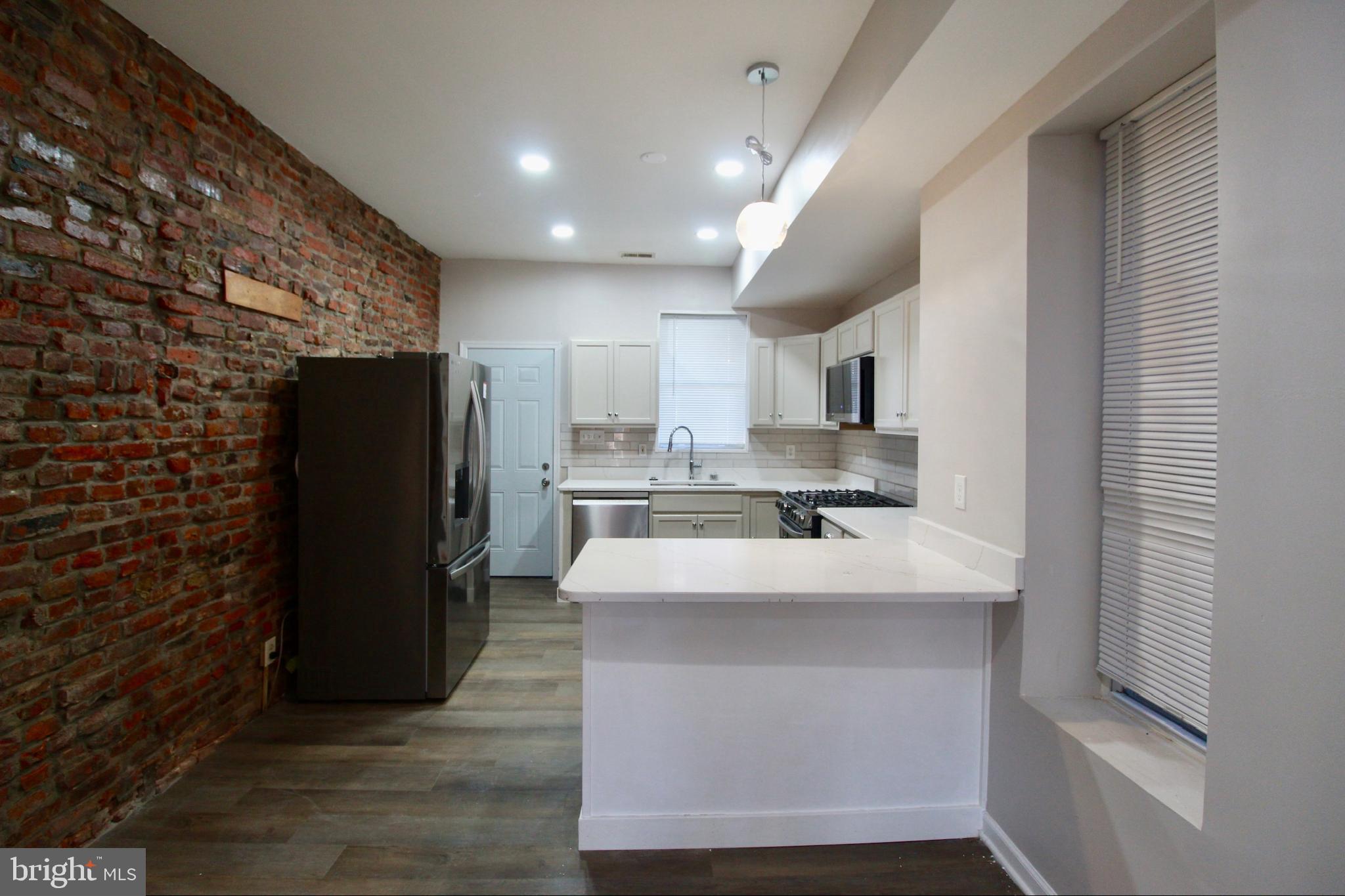 434 East 28th Street Baltimore, MD 21218 - Photo 9 of 37 a large kitchen with a large counter top stainless steel appliances and cabinets